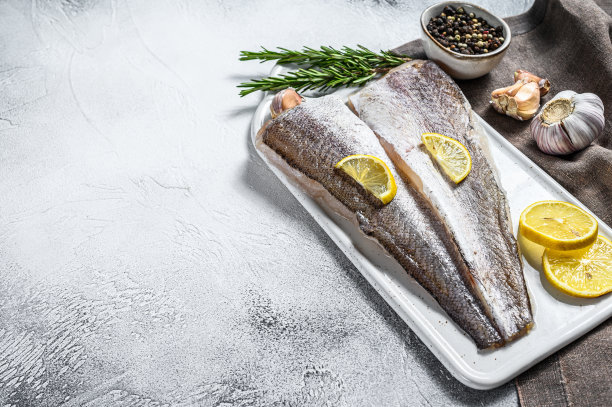 新鲜生鳕鱼片配胡椒和柠檬。白色背景。前视图。本空间图片下载