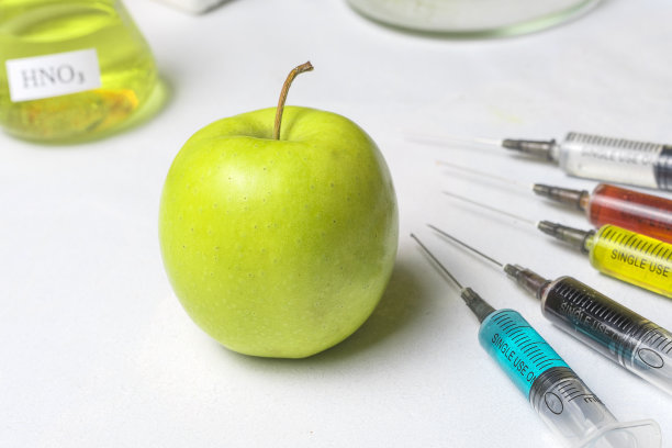 苹果用不同颜色的化肥制成的注射器。转基因和杀虫剂水果。图片下载