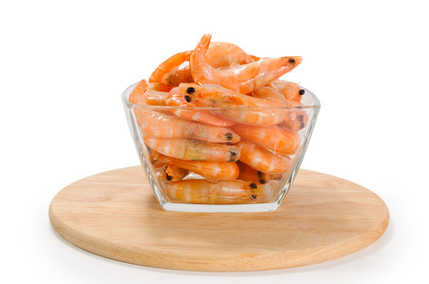 一堆冰壳虾，放在透明的玻璃碗里，放在白色背景的圆形木板上图片下载