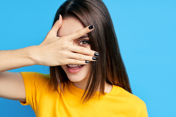 微笑的漂亮女人衣服眼睛用手，看透过手指用一只眼睛图片下载