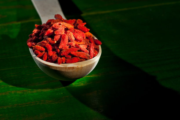 木勺里装着红枸杞。香料和调味料放在破旧的木板上。浆果堆在一起。作为一种艺术效果来对比戏剧性的光线。图片下载