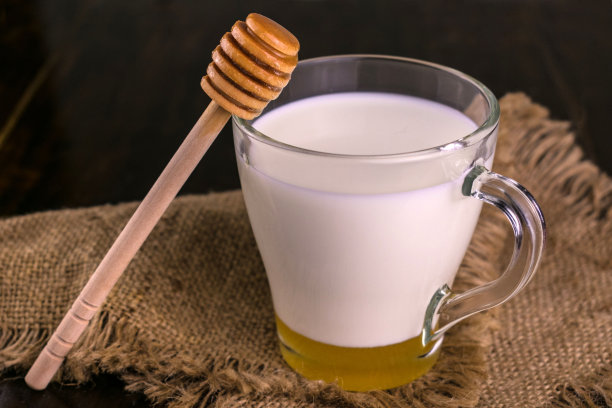 牛奶和蜂蜜在一个杯子在黑暗的背景。特写镜头图片下载