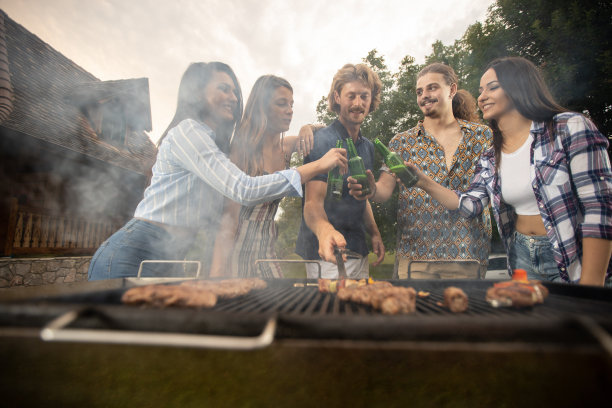 烧烤的烟从余烬升起，迎接它的是啤酒和年轻人图片下载