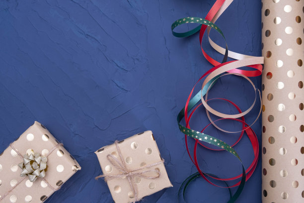蓝色背景的桌子上放着一个装有礼物和包装纸的盒子图片下载