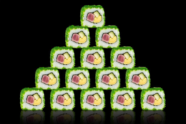 寿司搭配金枪鱼、奶酪和鳄梨做成金字塔形状。在一个黑色的背景反射。图片下载