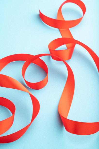 红色珊瑚缎带在蓝色柔和的背景。庆祝活动的概念。侧视图，拷贝空间。图片下载