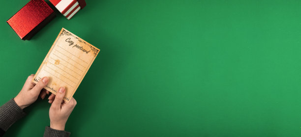 圣诞横幅，手握节日快乐贺卡，绿色背景与礼品盒和负空间图片下载