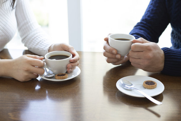 女人和男人的手拿着咖啡杯放在木桌的背景上图片下载