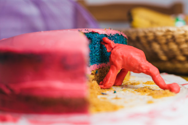 一个怪物形状的红色泥人模拟吃一个蓝色和红色的蛋糕，背景是水果。孩子们图片下载