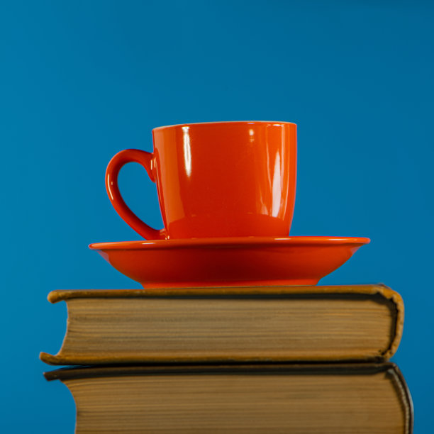 有咖啡的红杯子放在一堆书上。图片下载