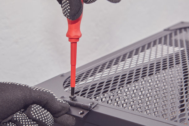杂工用螺丝刀拧紧电视架或架子金属框架门上的螺栓。图片下载