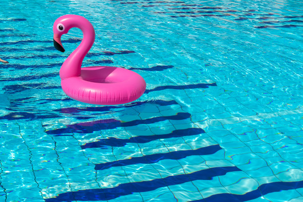 夏天的乐趣孤立。粉红色的充气火烈鸟在游泳池的水为夏季海滩背景。有趣的小鸟玩具。图片下载
