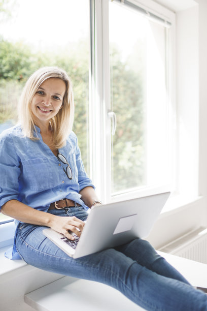 女商人在窗台上用笔记本电脑工作图片下载