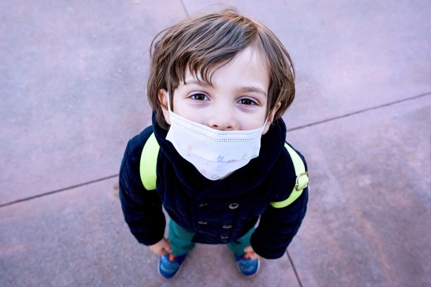 沉思烦恼的小男孩在学校用一个保护面罩看着摄像机图片下载