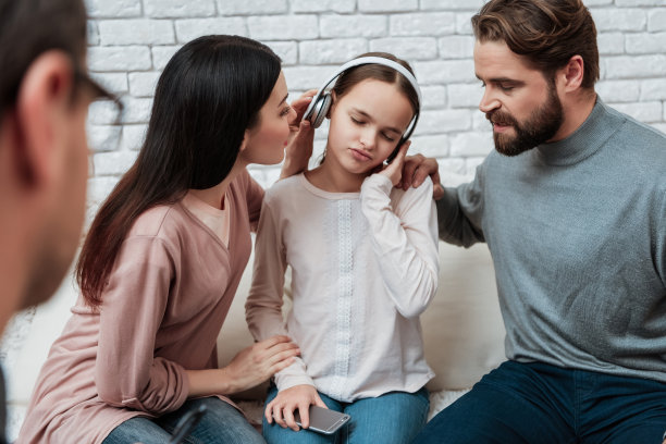 沮丧的父母试着去找戴着耳机的小女孩。儿童注意力不足。图片下载