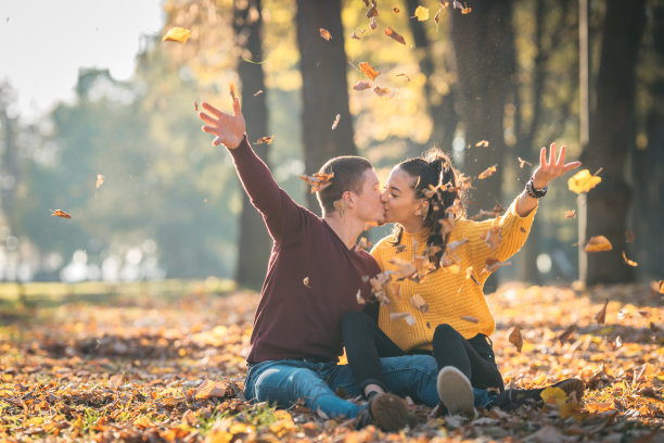 快乐的夫妇在秋天的公园里玩树叶图片下载