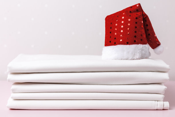 一叠干净的白床单和一顶圣诞帽。图片下载