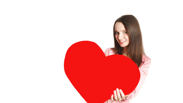 情人节快乐!一个美丽微笑的白人年轻女人的肖像抱着巨大的红心，看着相机与牙齿的微笑在白色的背景。副本的空间。浪漫的概念。图片下载