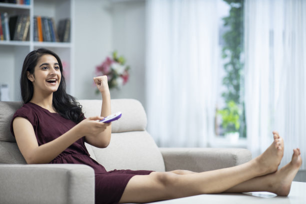 年轻女子坐在家里的沙发-库存照片图片下载