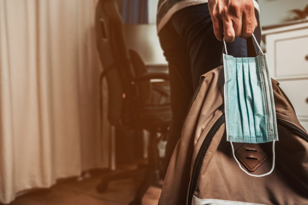 一名男子拿着一个面具和背包，从办公室底部拍摄图片下载