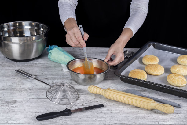 糕点女士双手搅拌蛋黄釉，放在刚烤好的甜点加工台上。摄影博客和社交媒体。有选择性的重点图片下载