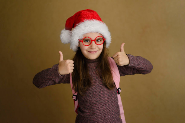 可爱的小女孩戴着红眼镜，戴着圣诞帽，竖起大拇指。一切都很好。培训，假期，学校假期，折扣和黑色星期五的概念。图片下载