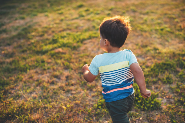 上面的视图照片，一个白人男孩在一个夏天的晚上在操场上玩耍和奔跑图片下载