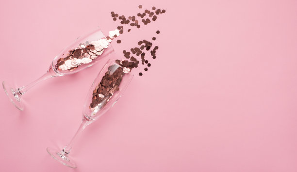 聚会的概念。上面的俯视视图近距离的照片两个香槟长笛充满五彩纸屑孤立在帕特尔粉背景与copyspace图片下载