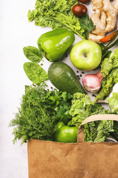 绿色素食在全纸质购物袋，蔬菜和水果在白色的背景。超市购物，生食和清洁饮食理念。健康的食物图片下载