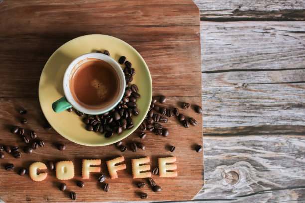 白色杯子里的咖啡，烤好的咖啡豆，木头背景上的英文小脆面包。副本的空间。从以上观点。水平方向。图片下载