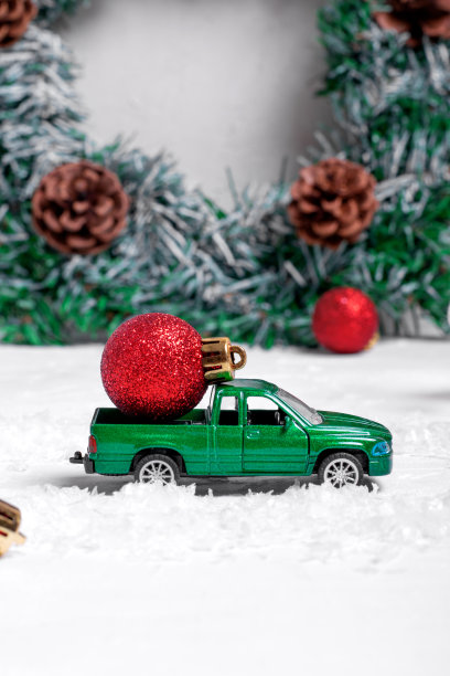 人造雪上有红色小玩意的绿色玩具小卡车图片下载