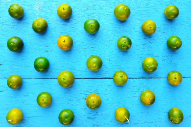黄绿色的酸橙，酸橙或菲律宾酸橙热带水果图案在明亮的蓝色木材背景。亚洲夏季柑橘类果实平铺组成。图片下载