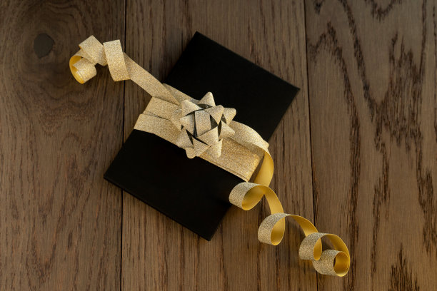 一个木制古董桌子上的礼物特写。带金色蝴蝶结的黑色盒子。图片下载