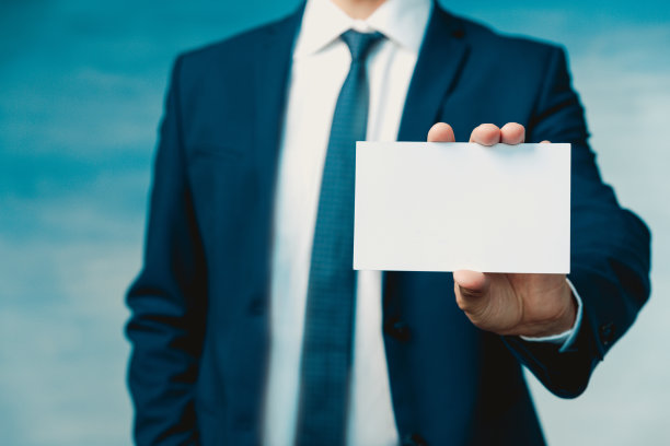 一位穿着蓝色西装、打着领带的商人的手拿着一张空白的纸，向镜头特写展示图片下载