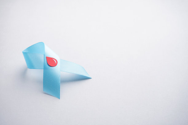 灰色背景上带着血滴的蓝丝带，平躺着。11月14日世界糖尿病日。空间的文本。糖尿病的概念。图片下载