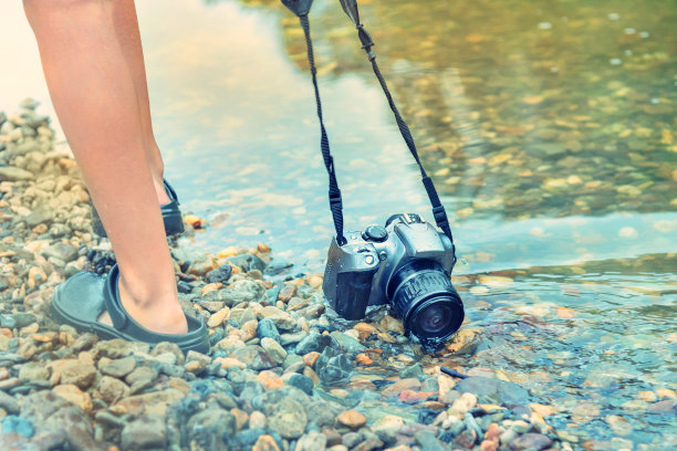 数码单反相机浸泡在岩石底部的水中。防水装置的概念和可靠性图片下载