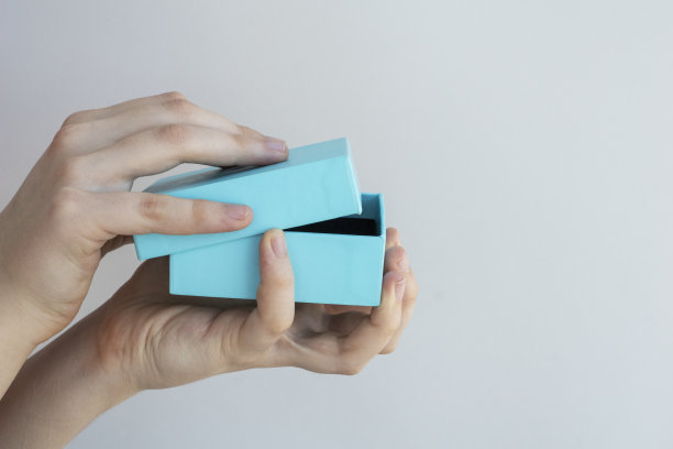 女性手拿着蓝色的方形礼品盒，开始打开它的灯光背景，文字复制空间，图片下载