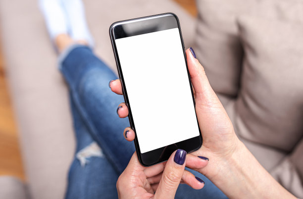 一个躺在沙发上的女人手里拿着智能手机。手用智能手机。图片下载