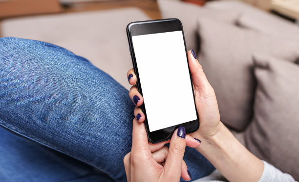 一个躺在沙发上的女人手里拿着智能手机。手用智能手机。图片下载