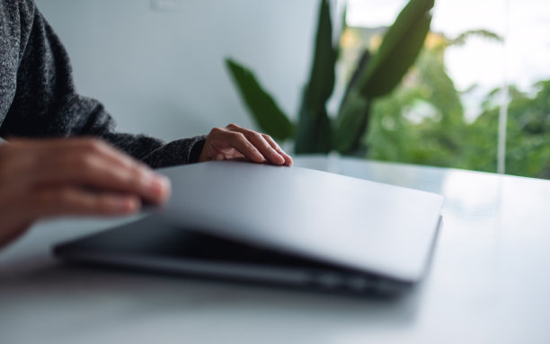 在桌上用完笔记本电脑后，双手合拢并打开图片下载