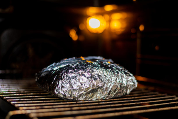 铝箔肉放入烤箱。做饭、烤猪肉。图片下载