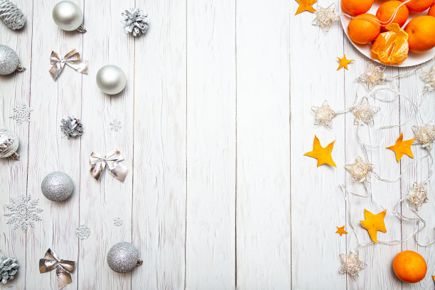用橘子、银色圣诞装饰品、花环灯和一个白色木板背景上有棉花糖的杯子组成的圣诞装饰品。新年或圣诞节背景与地方文字。图片下载