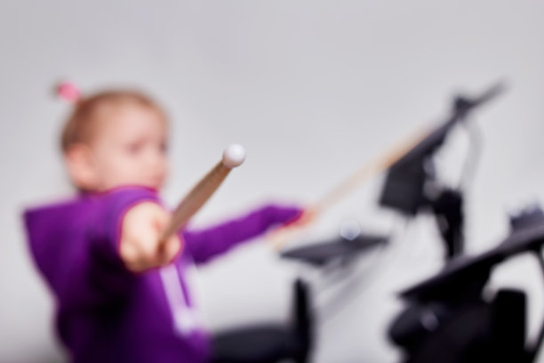 快乐的白人小女孩鼓手。在音乐学校学习打鼓或使用电子鼓的女孩。情感上的肖像。模拟，灰色背景的工作室。免费的广告空间。图片下载