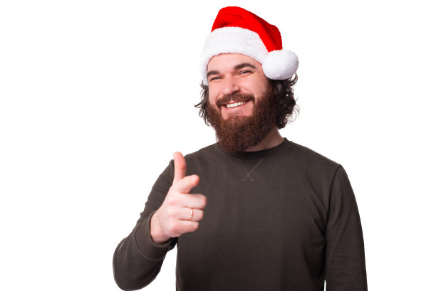 积极的胡子潮人戴着圣诞老人的帽子，指着相机图片下载