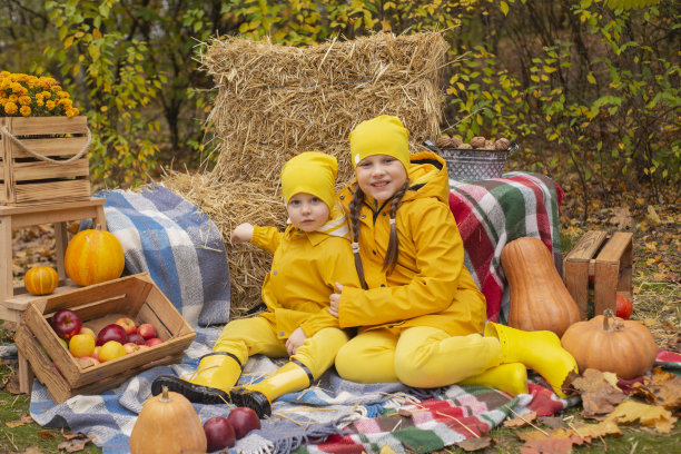 可爱快乐的小男孩和一个女孩-兄妹-穿着相同的黄色服装和帽子附近的秋天装饰品-南瓜，苹果，毯子，干草。舒适,家庭图片下载