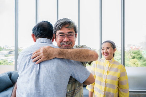 年长的男性朋友在客厅互相拥抱问候。图片下载