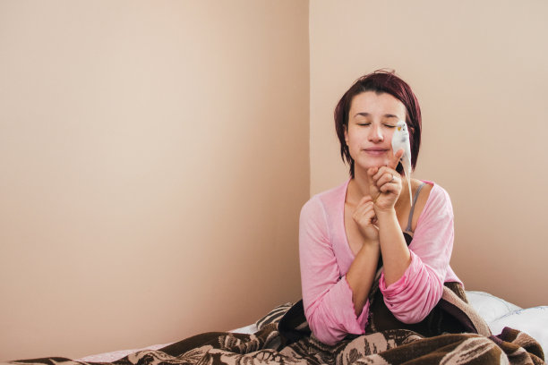 女人在床上玩她的鹦鹉库存照片图片下载