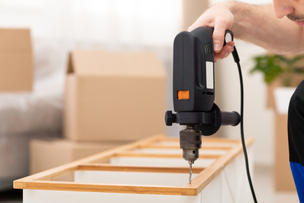 无法辨认的家具组装员在室内用钻机组装橱柜架图片下载