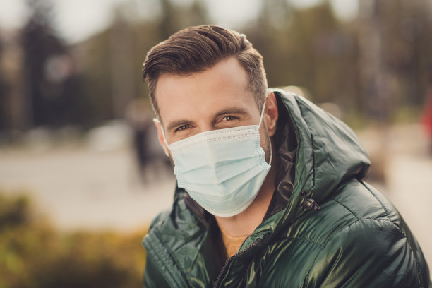 正年轻男子穿着绿色风衣面罩在城市街道外的照片图片下载