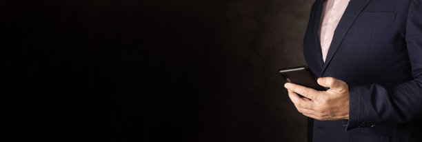 联系我们联系概念与拷贝空间。一个拿着手机的商人的手。黑色背景上的横幅图片下载